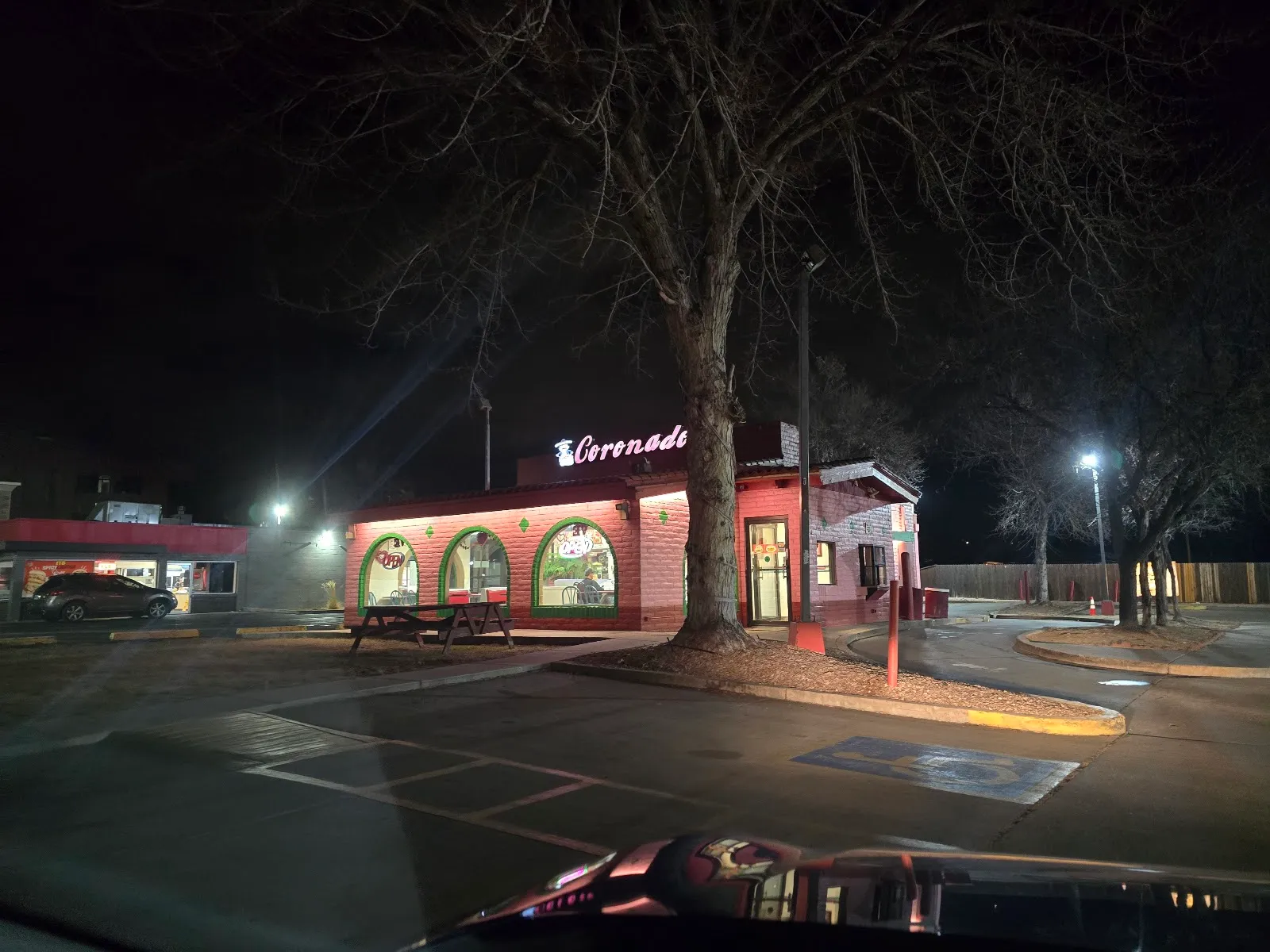 Coronados Mexican Food at night, a brick building with green arched windows and a lit Coronado's sign