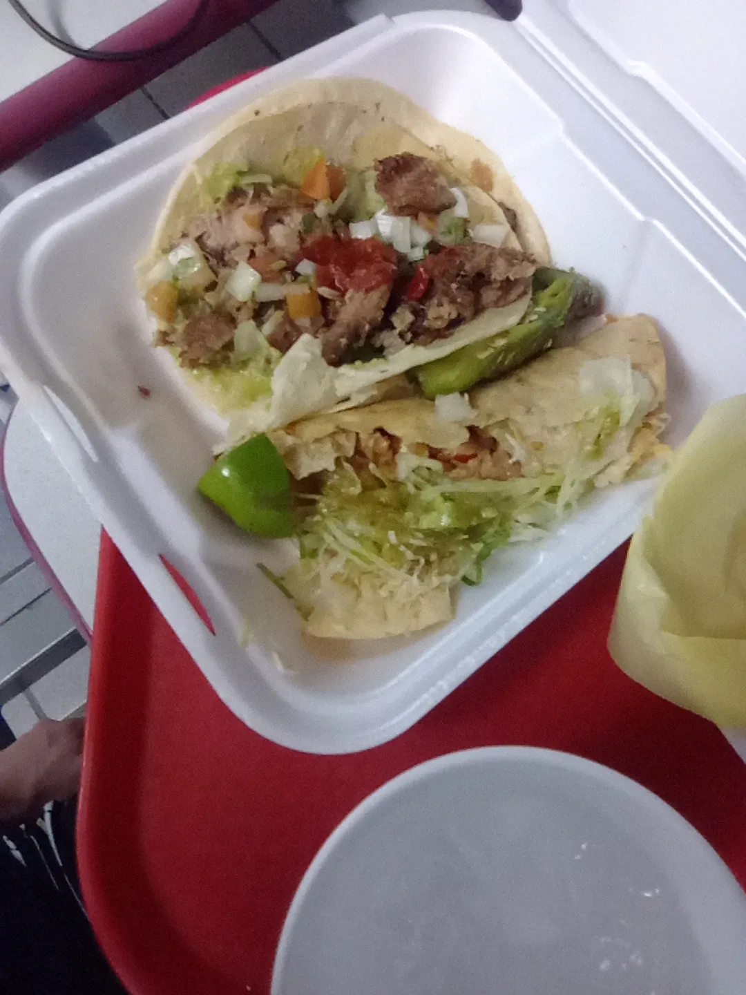 Soft corn tacos and a roasted jalapeno in a takeout box