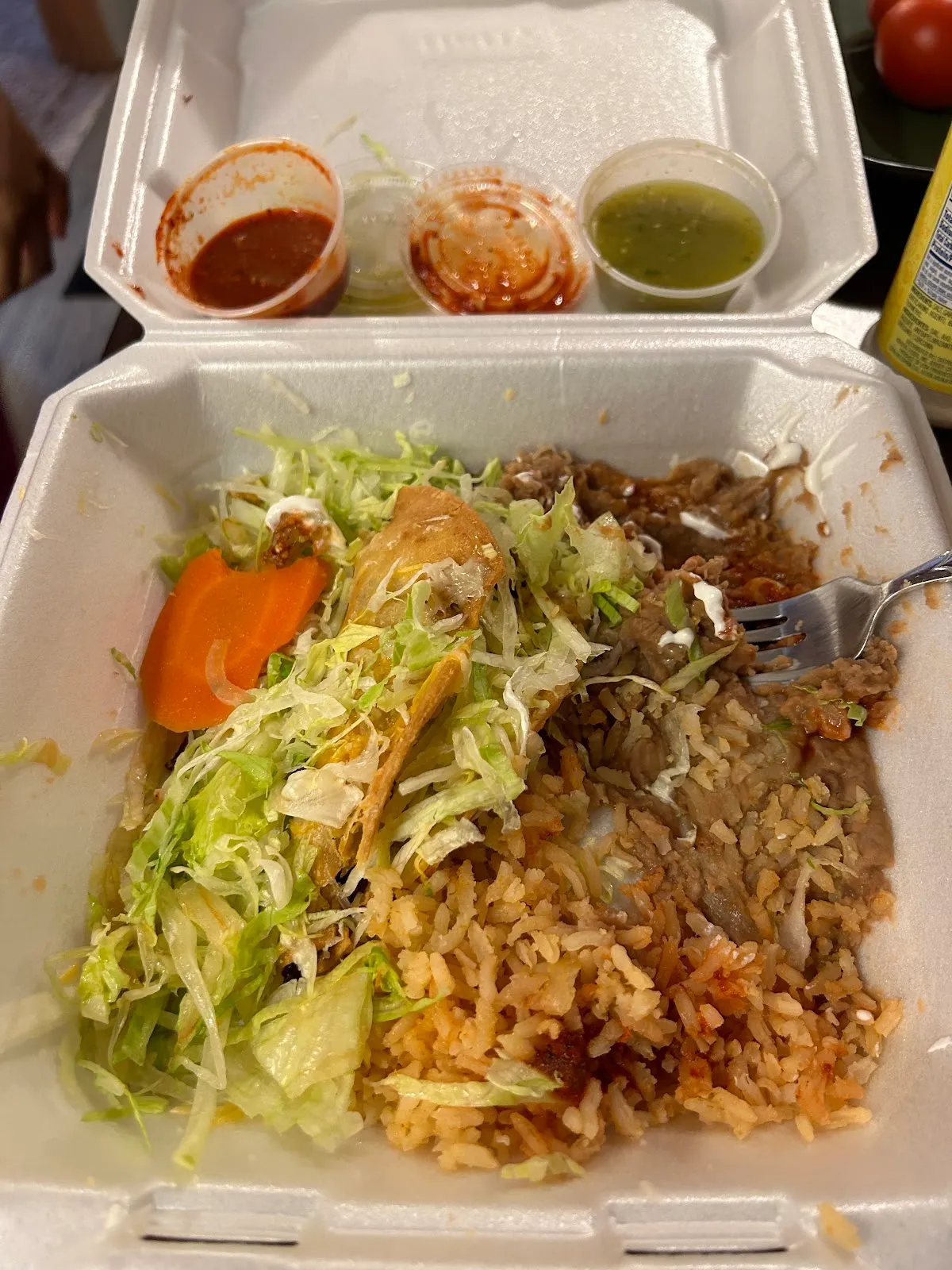 Combo plate with a rolled taco, Spanish rice, refried beans, lettuce, and salsas