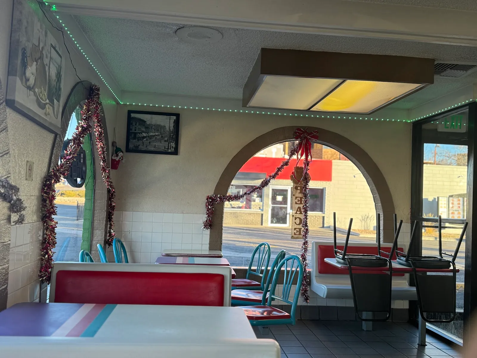 Dining room with arched windows, red and teal booths, and green string lights